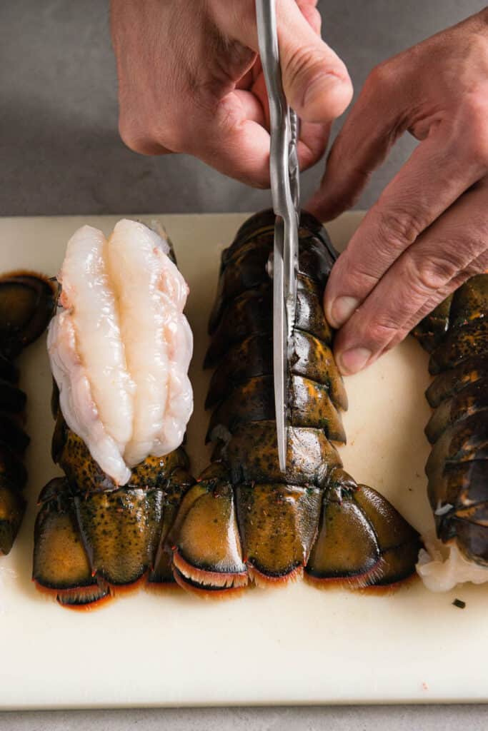 cutting the spine of a lobster tail with scissors