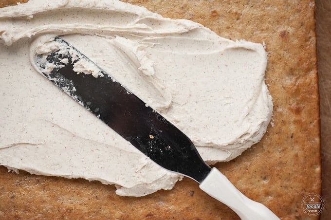 Spreading vanilla bean frosting on top of a homemade banana bar