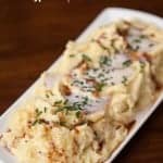 mashed potatoes on white platter on top of a wooden table