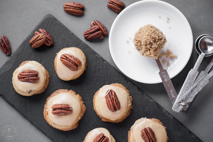 A bunch of brown sugar pecan cookies sitting on a dish, with pecans