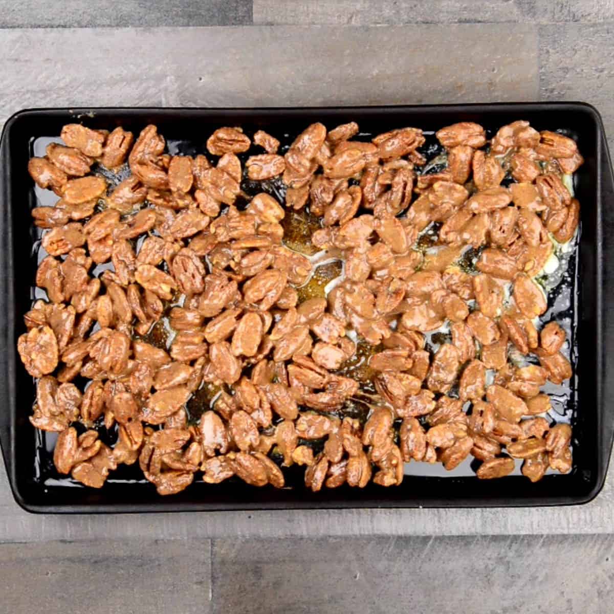 pecans coated in egg white and sugar on baking sheet