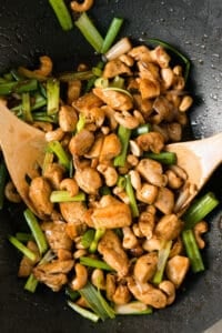Cashew Chicken in wok with wooden spoons