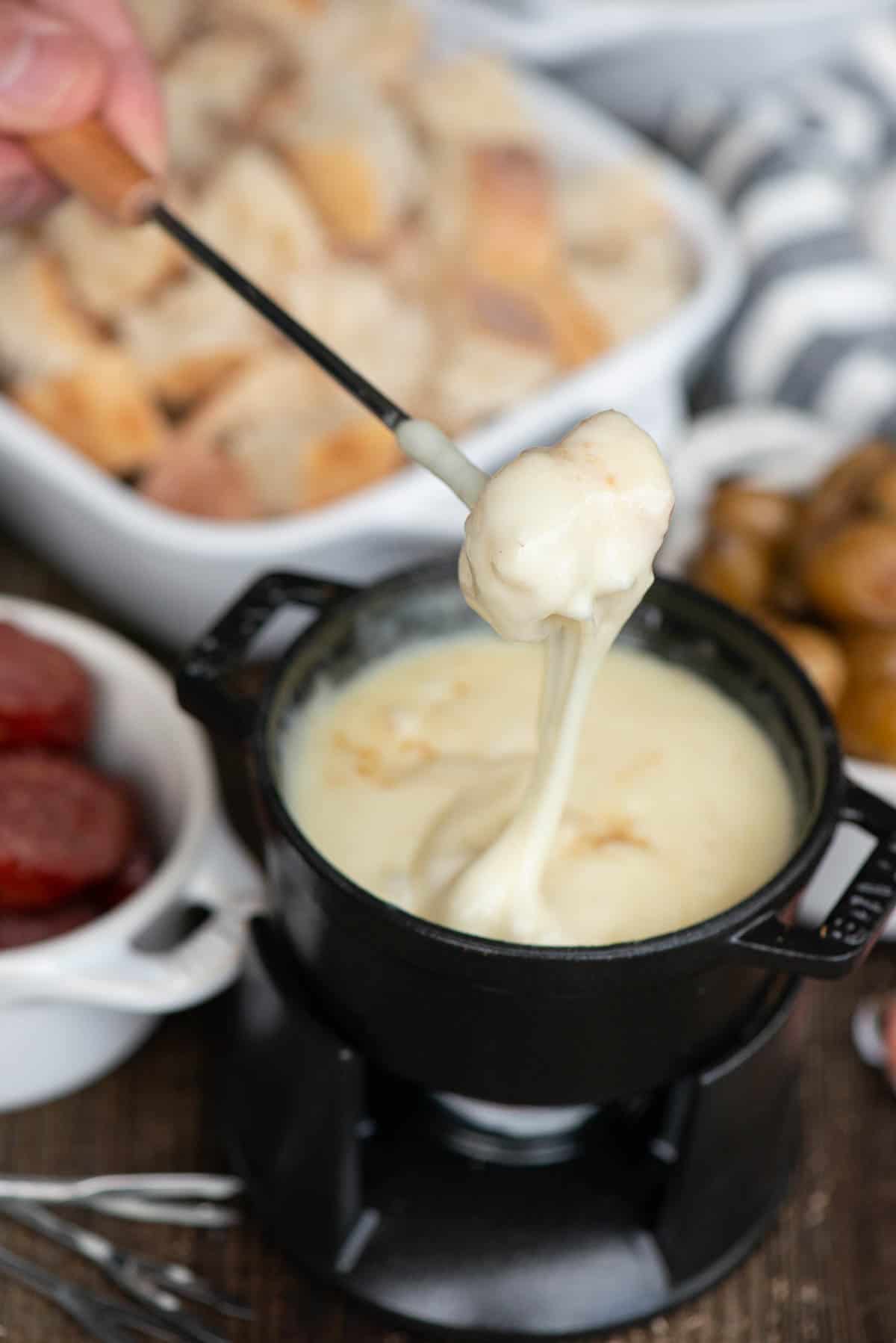 Melted Swiss cheese fondue with assorted fondue dippers.