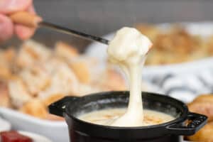 dipping a piece of bread into homemade cheese fondue.