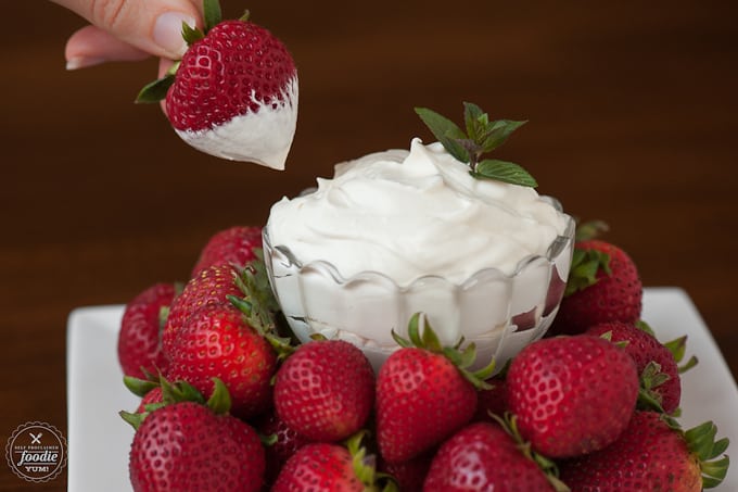 a strawberry being dipped in cheesecake fruit dip
