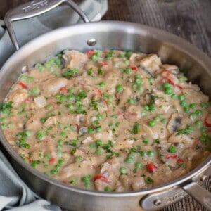 homemade chicken a la king with mushrooms and peas in gravy in pan.