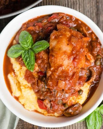 white bowl with polenta and chicken stew in tomato sauce