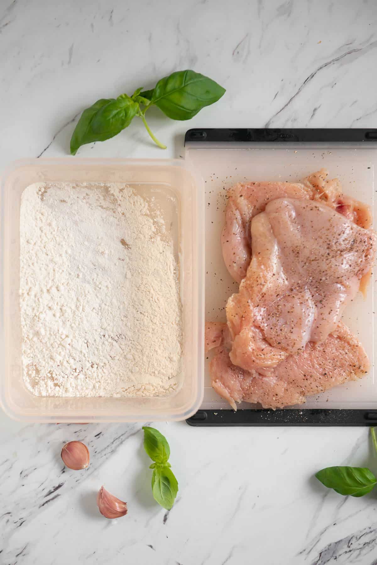 chicken breasts next to flour.