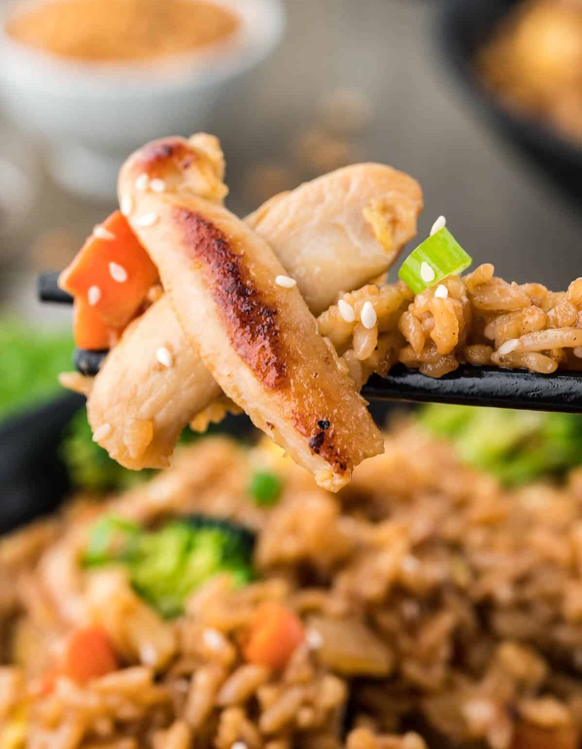 close up of chicken fried rice on chopsticks.