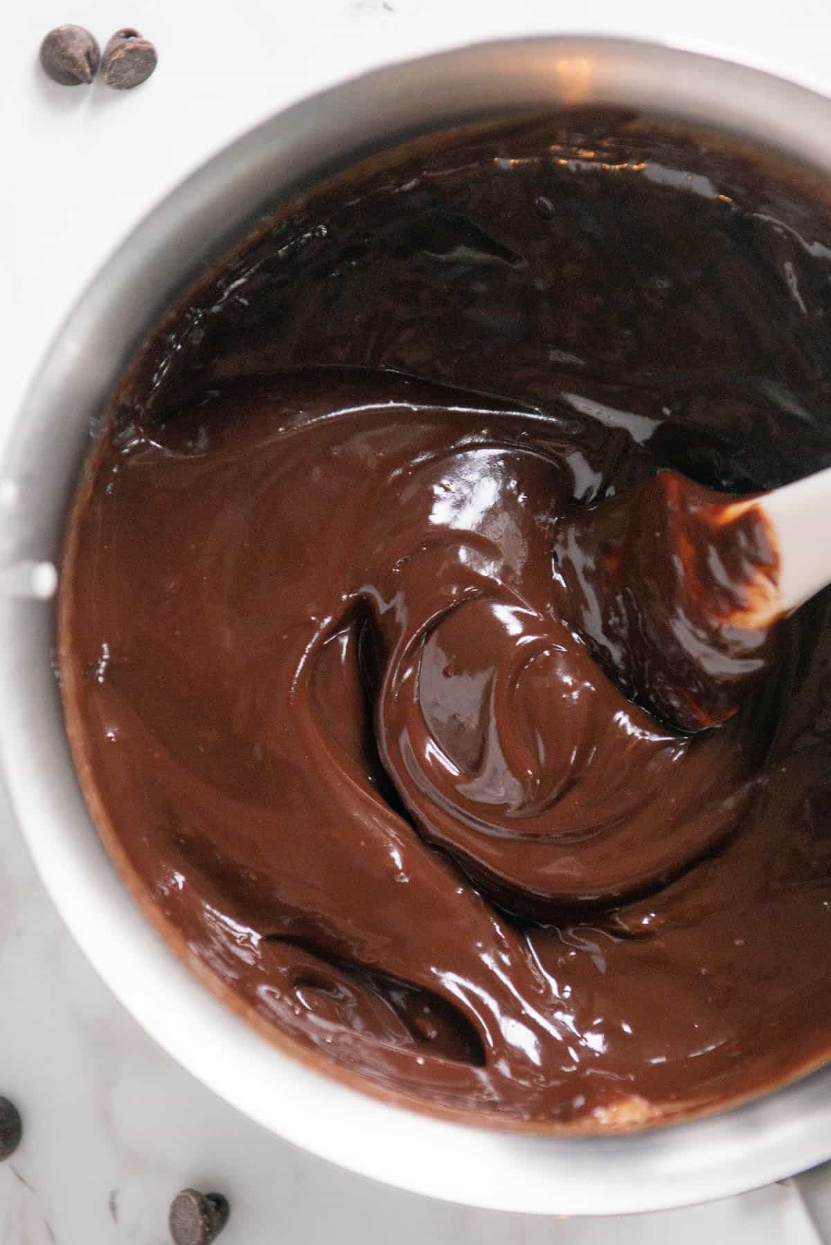 Stirring warm chocolate fondue in pot.
