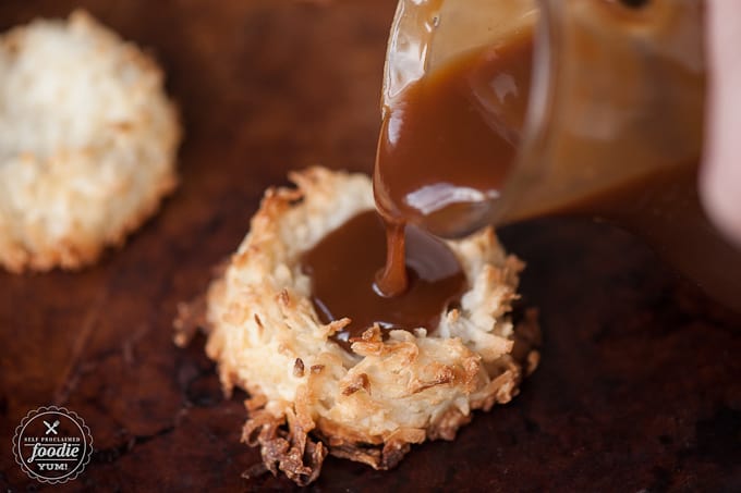pouring caramel sauce onto a coconut macaroon cookie