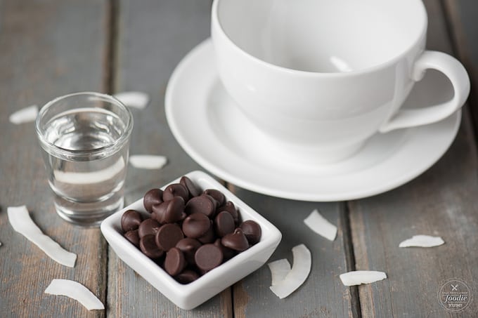 a small dish of chocolate chips, with a white cup next to it