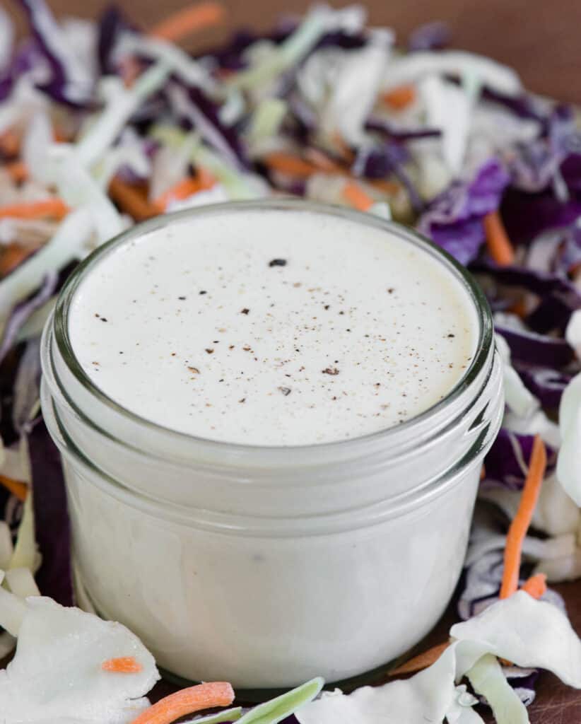 mason jar of homemade Coleslaw Dressing with cabbage