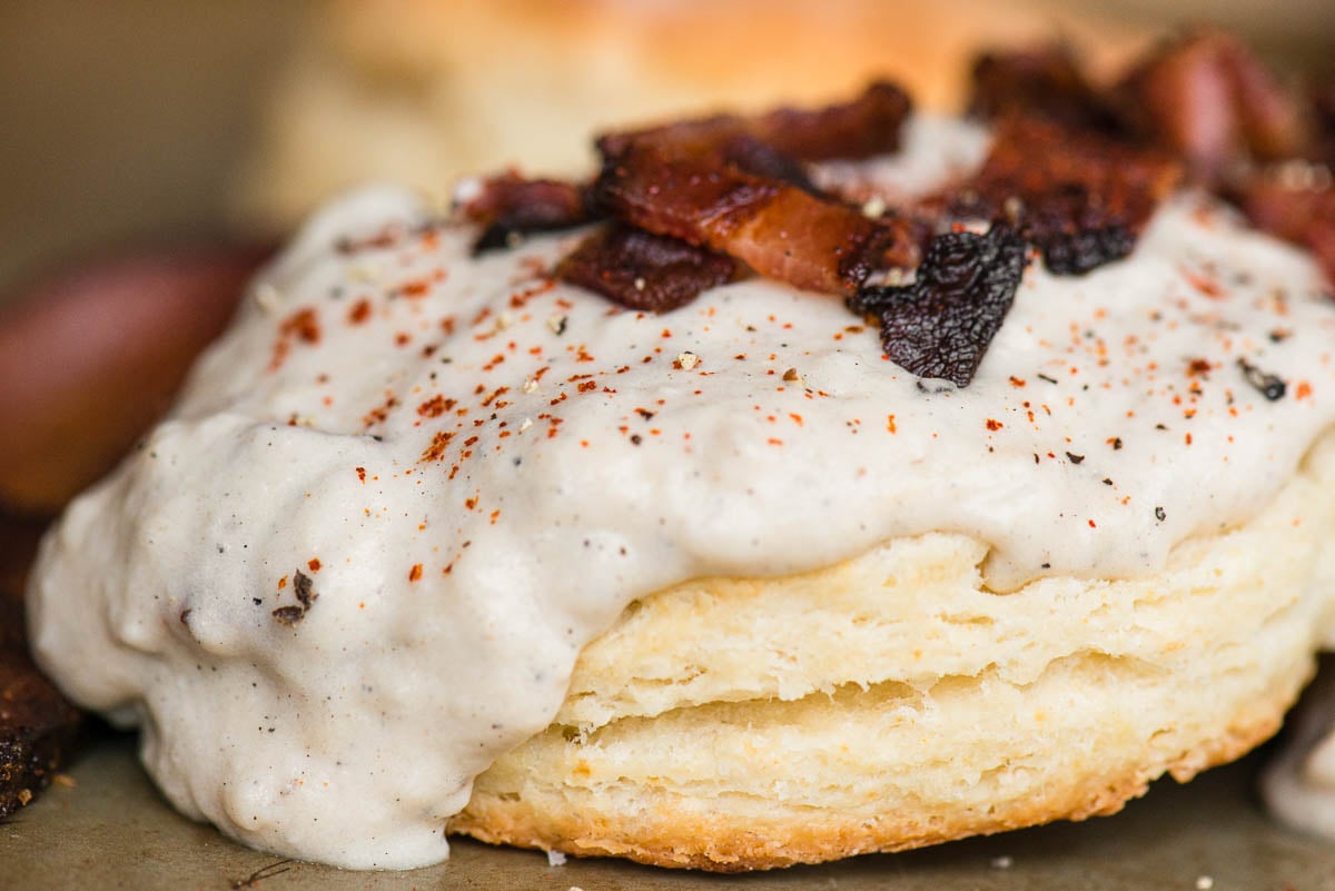 close up of a biscuit with bacon gravy and bacon bits.