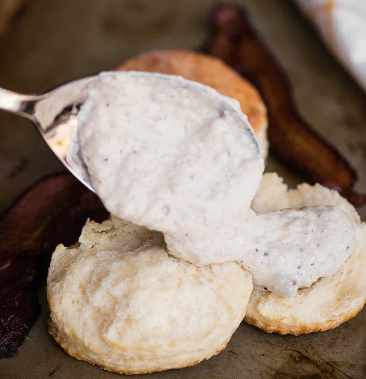 bacon gravy getting spooned onto biscuits.