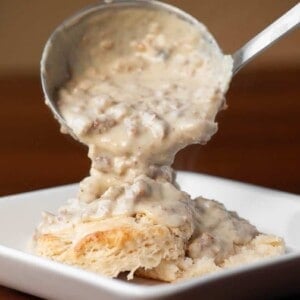 adding sausage gravy to buttermilk biscuits.