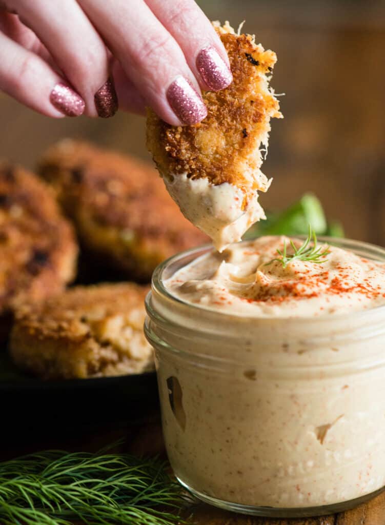 dipping homemade crab cakes into remoulade sauce.