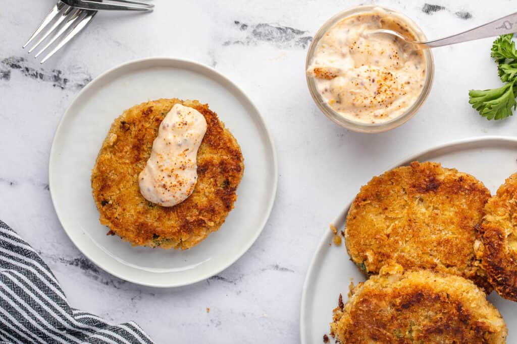topping crab cakes with remoulade sauce.