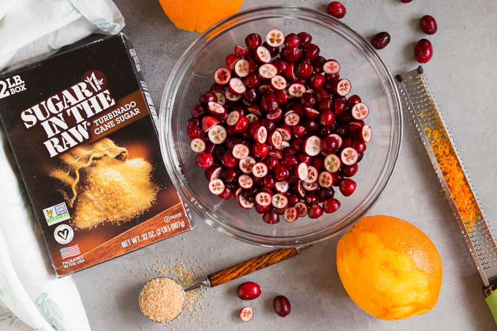 bowl of fresh cranberries cut in half with sugar and orange