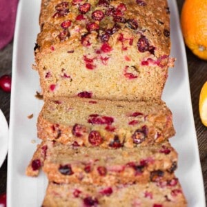 sliced quick bread with orange and cranberry on white platter