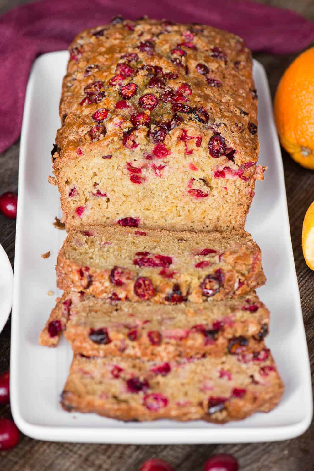 sliced quick bread with orange and cranberry on white platter