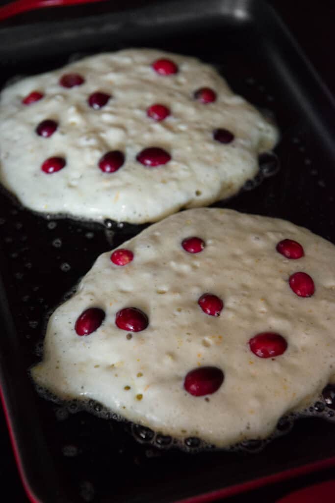 Buttermilk Pancakes on griddle with fresh cranberries