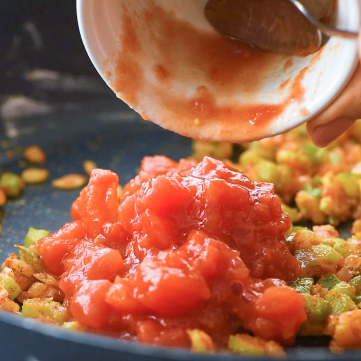 adding tomatoes to pan for crawfish etouffee recipe.