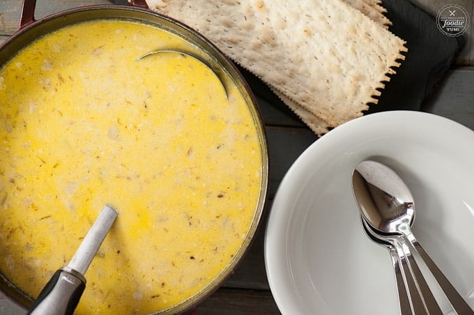 top view of pot of soup, stack of bowls with spoons, crackers