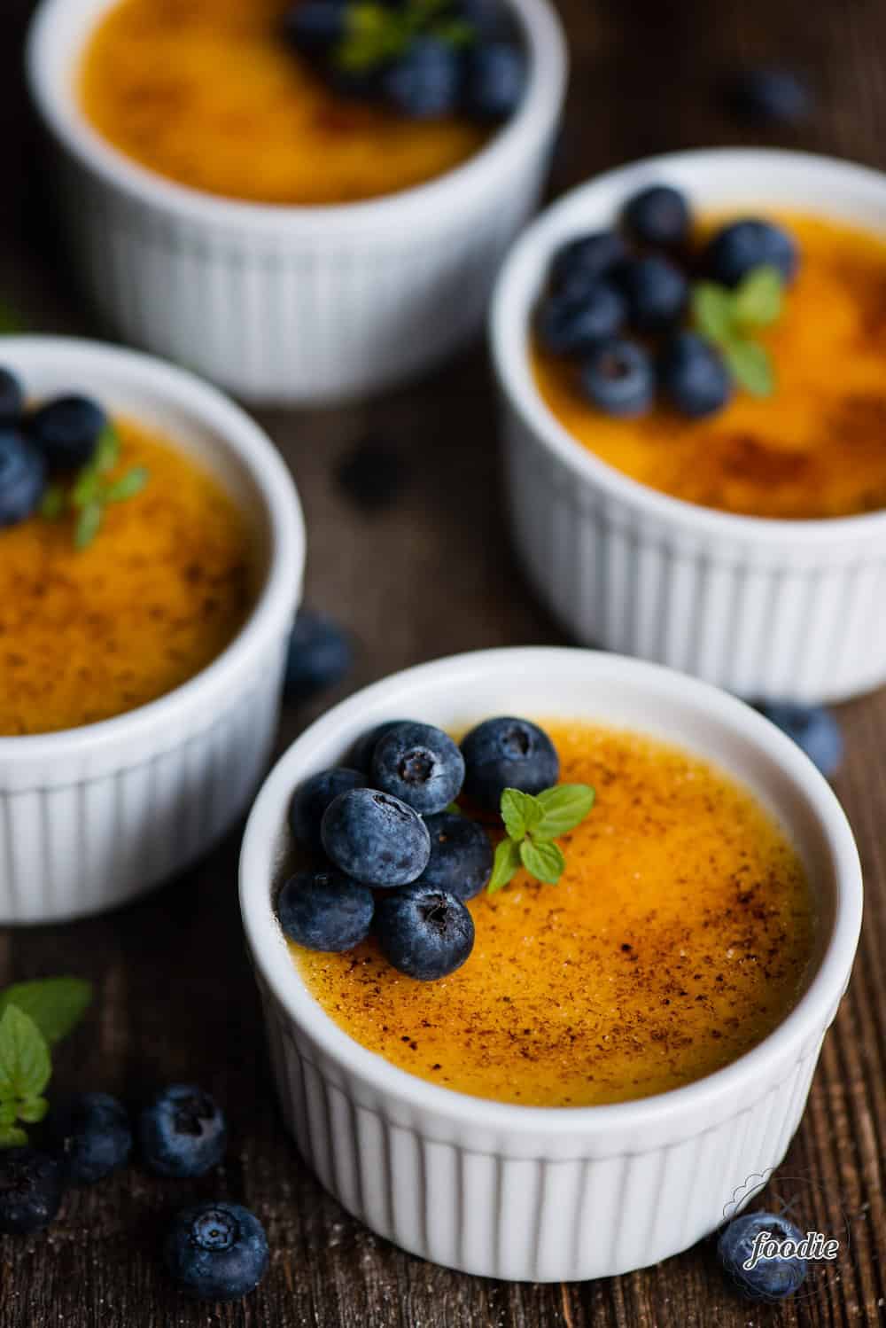 ramekins of creme brulee with blueberries on top