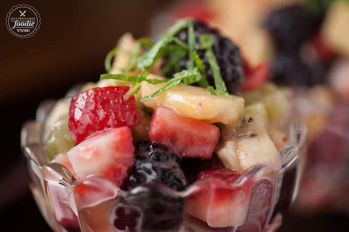 A close up of fruit salad with lemon curd dressing and sliced mint