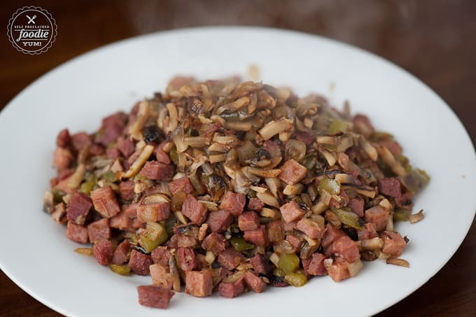 a plate of cooked ham with mushrooms, onions and peppers