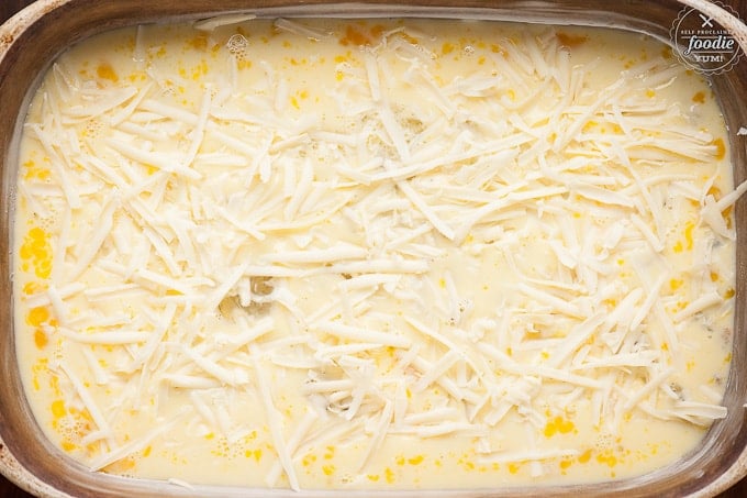 shredded cheese on egg in baking dish for breakfast casserole prior to cooking