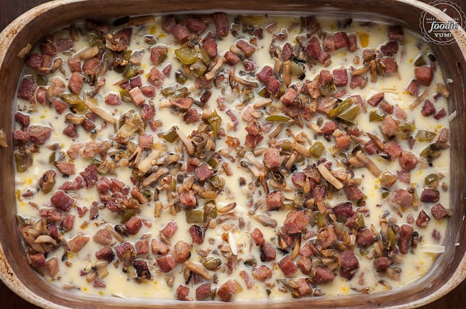 cooked ham, mushrooms, peppers on egg in baking dish for breakfast casserole