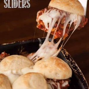 lifting a mozzarella stuffed meatball slider out of a pan