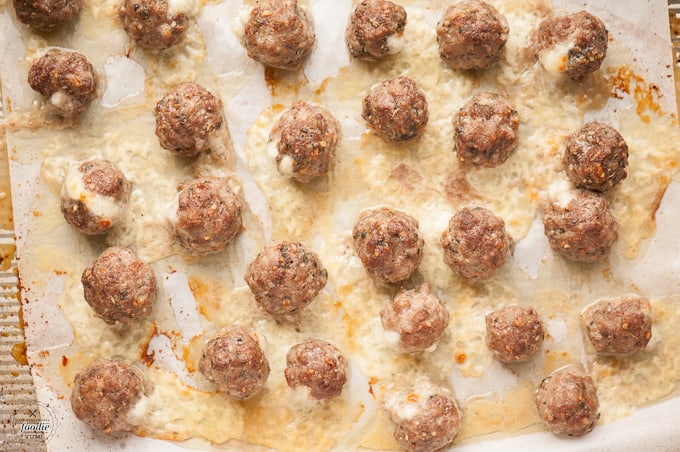 cooked mozzarella stuffed meatballs on baking sheet