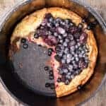 dutch baby with berries on top with slice taken out