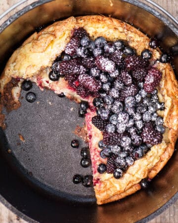 dutch baby with berries on top with slice taken out