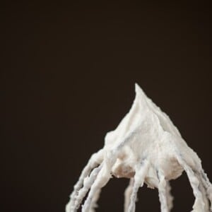 a close up of eggnog frosting on a whisk