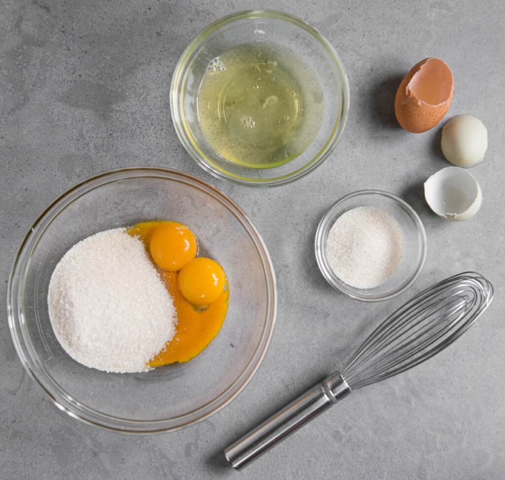 separated eggs in bowls with sugar