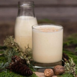 homemade eggnog in glass with greenery and nutmeg as decoration