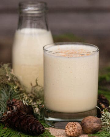 homemade eggnog in glass with greenery and nutmeg as decoration