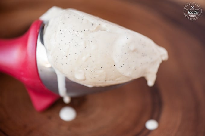 Red ice cream scoop with melting vanilla bean ice cream