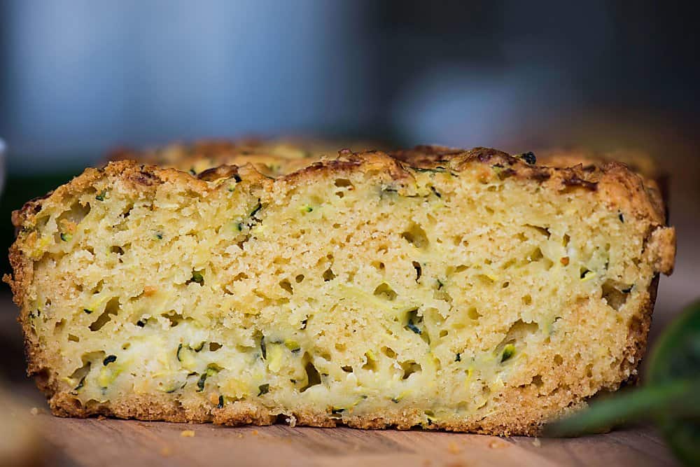 A close up of a piece of cheddar zucchini bread