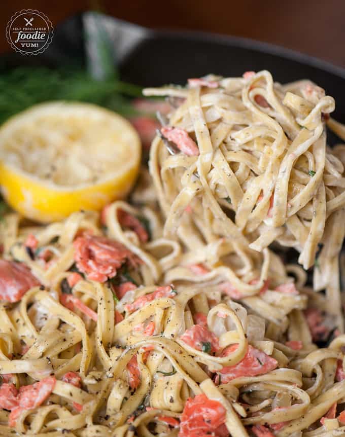 serving scoop of fettucine with cream sauce an salmon