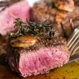 perfectly cooked filet mignon steak cut in half with garlic and herbs