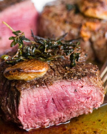 perfectly cooked filet mignon steak cut in half with garlic and herbs