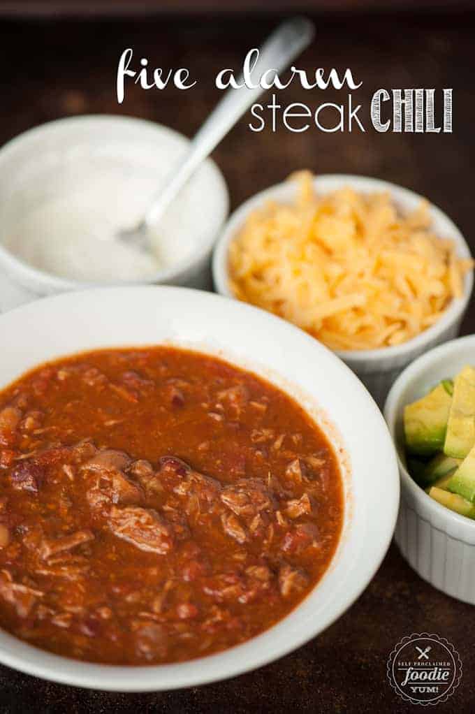 Steak Chili in bowl with sour cream, cheese, and avocado