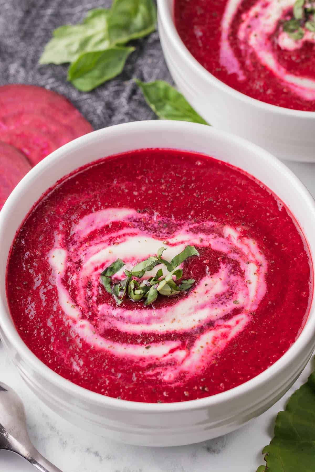 homemade fresh beet soup with swirl of cream and basil.