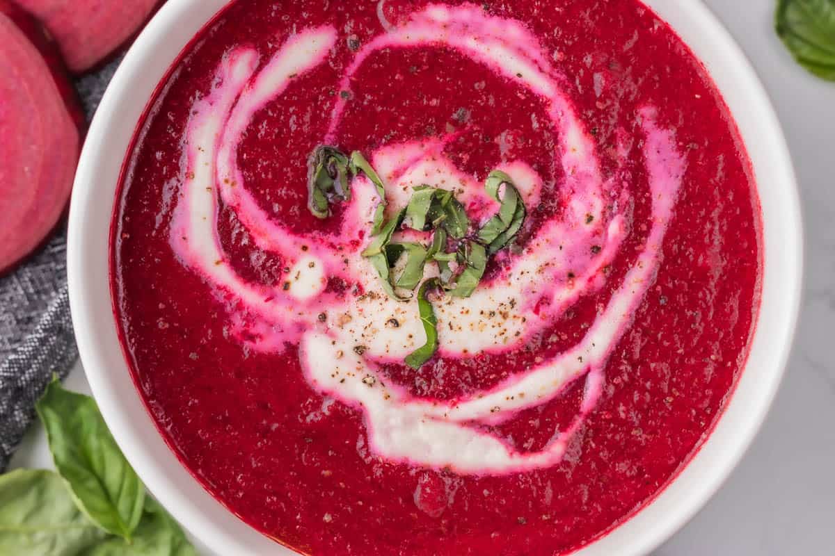 bowl of fresh beet soup with cream and cracked pepper.