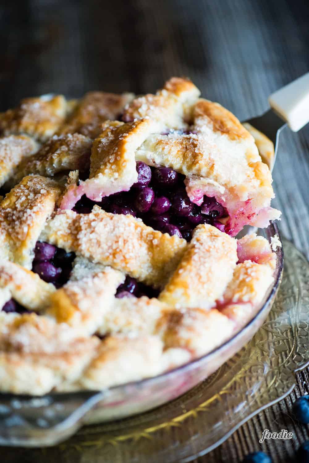 lifting a slice of fresh blueberry pie out of the pie dish